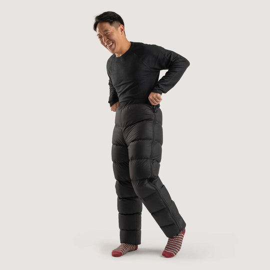 Studio front view of a man wearing a black Feathered Friends Helios down pants
