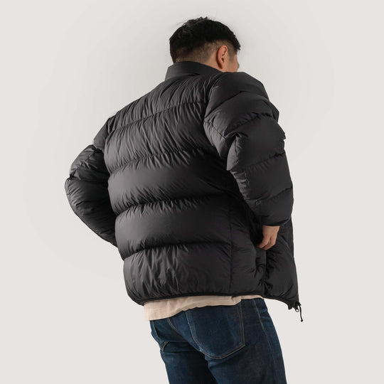 Studio back view of a man wearing a black Feathered Friends Helios jacket