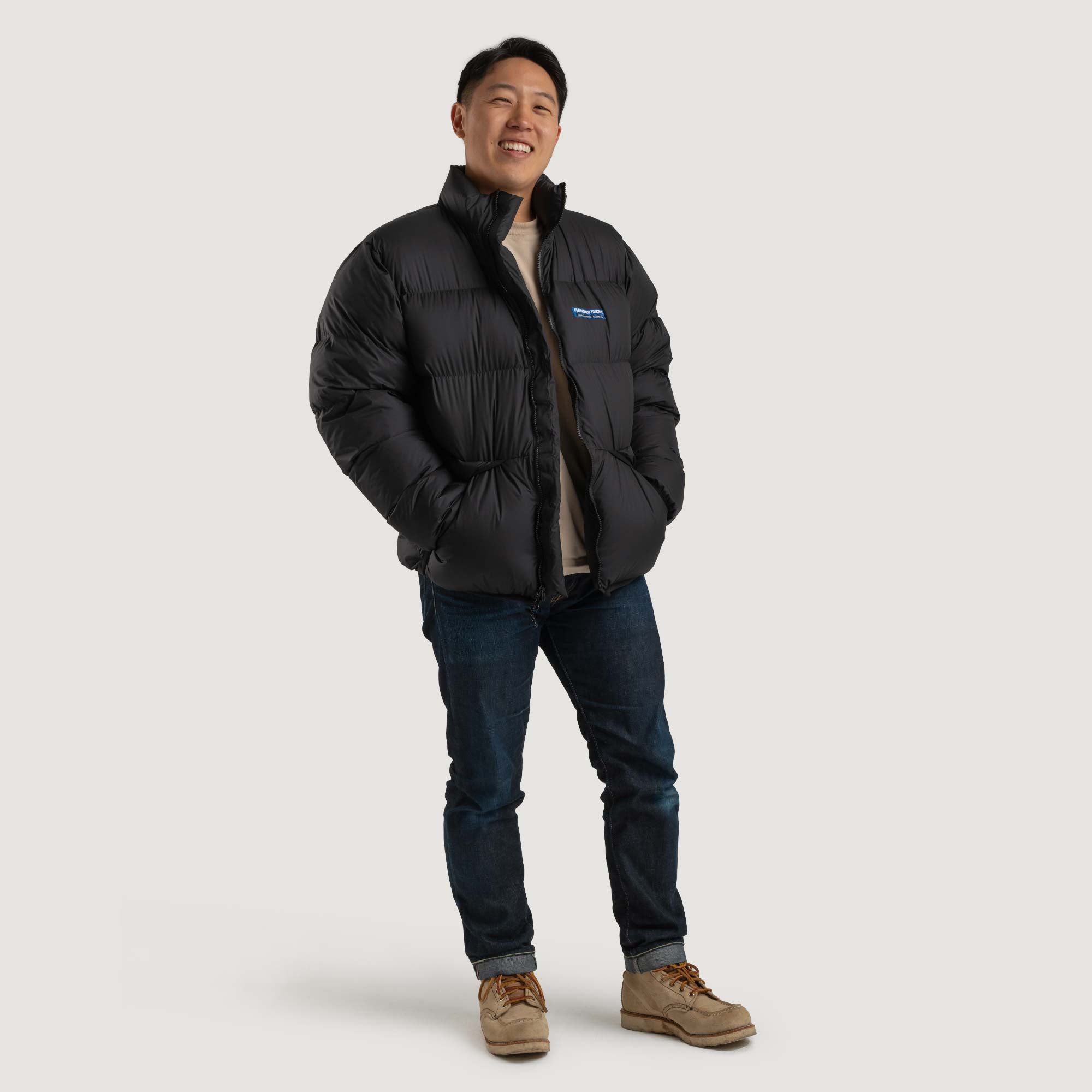 Studio front view of a man wearing a black Feathered Friends Helios jacket